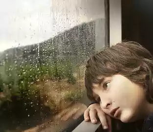 garçon qui regarde la pluie