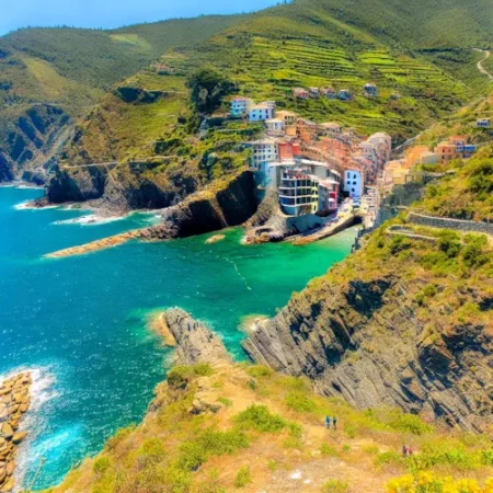 Vue côtière du Sentiero Azzurro avec des falaises escarpées et des villages colorés perchés sur la côte méditerranéenne.